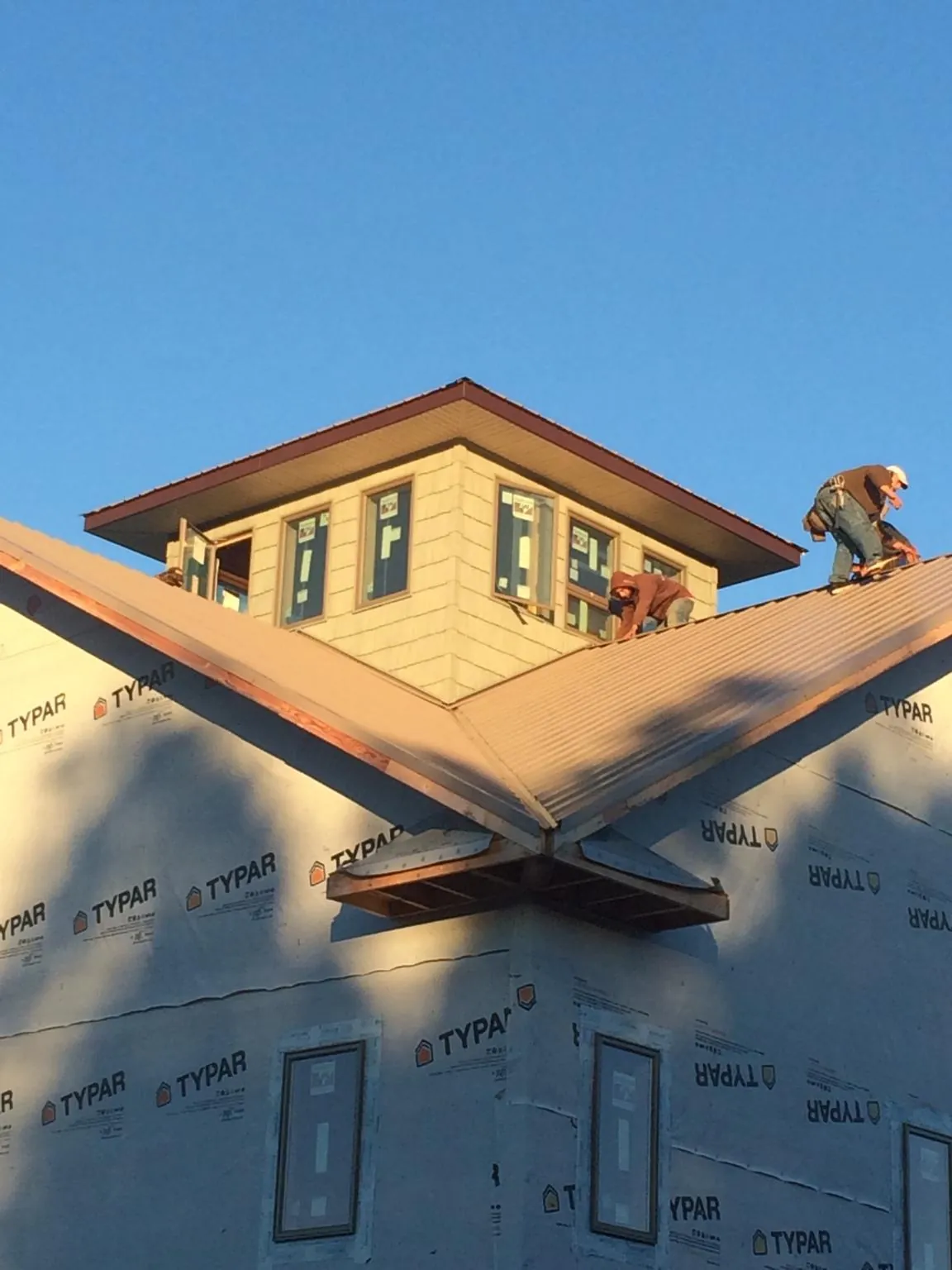 Roofers working around a rooftop cupola on a new metal roof at sunset — Roof Waterproofing in Franklin by Roofing Brothers